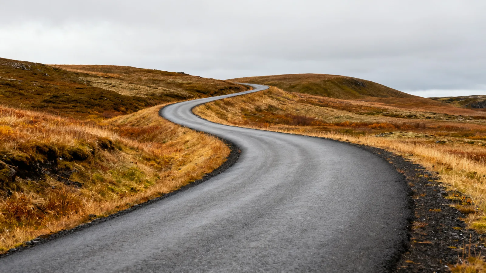 Anonymous winding paved road through Icelandic low hills