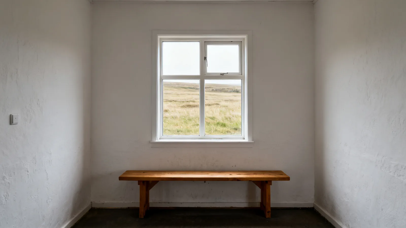 Empty indoor wooden bench beside a rural window